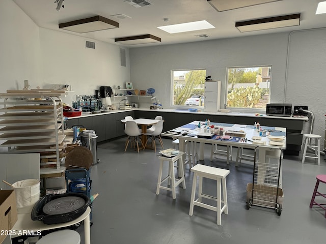 home office with a workshop area, concrete floors, and visible vents