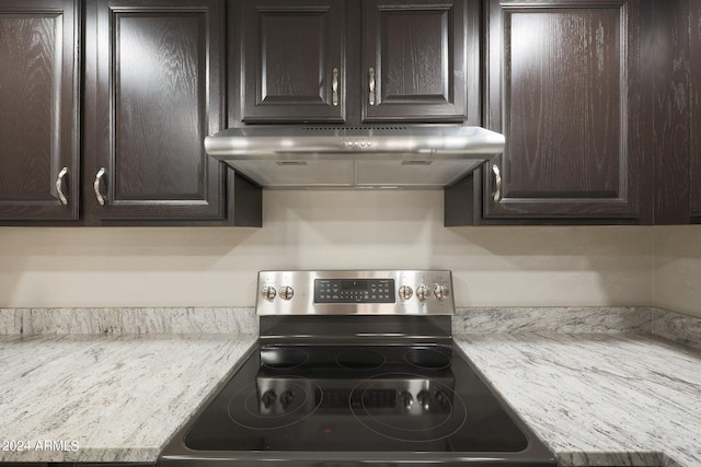 kitchen featuring dark brown cabinetry, under cabinet range hood, and stainless steel electric range