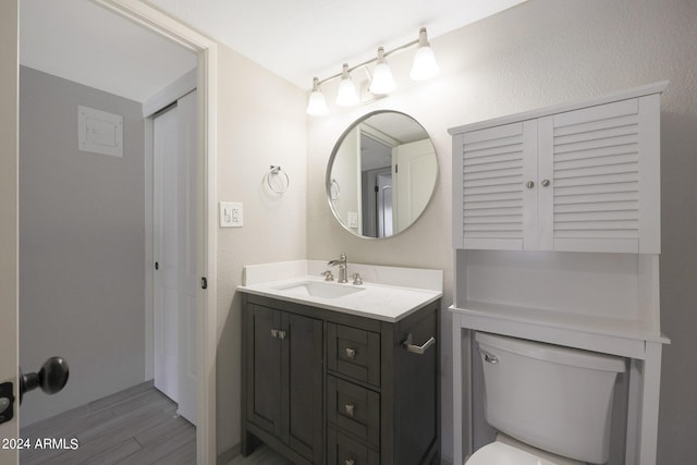 bathroom with toilet, wood finished floors, and vanity