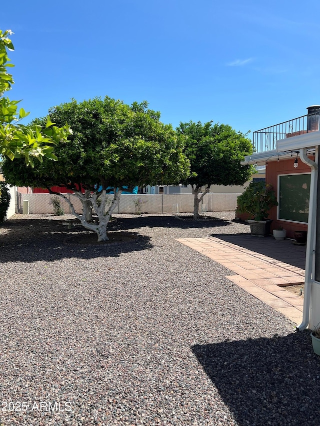 view of yard featuring fence, a patio, and a balcony