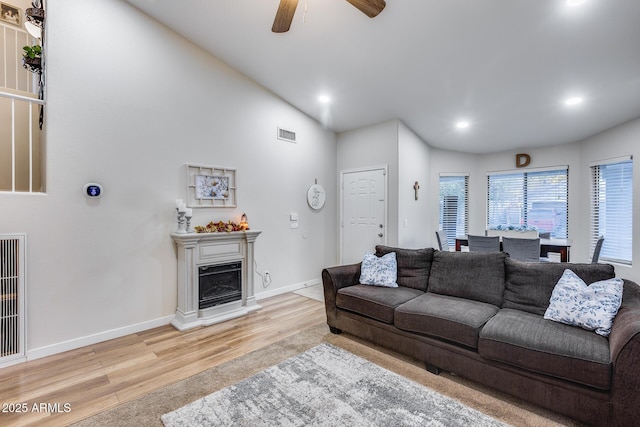 living room featuring ceiling fan, light wood-type flooring, and vaulted ceiling