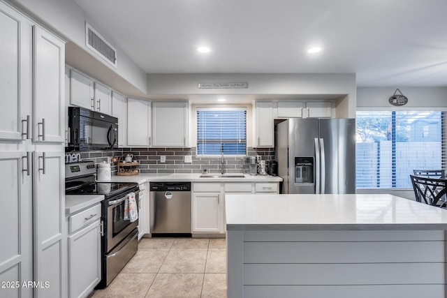 kitchen featuring white cabinetry, sink, decorative backsplash, light tile patterned flooring, and appliances with stainless steel finishes