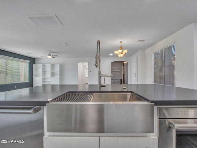 kitchen featuring arched walkways, visible vents, a ceiling fan, open floor plan, and dark countertops