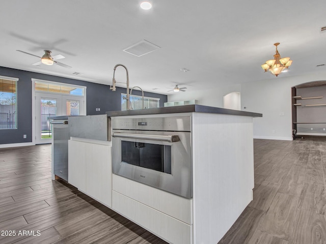 kitchen with stainless steel oven, open floor plan, and dark wood-style flooring