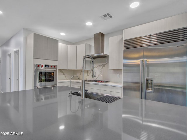 kitchen with visible vents, decorative backsplash, stainless steel appliances, wall chimney range hood, and recessed lighting