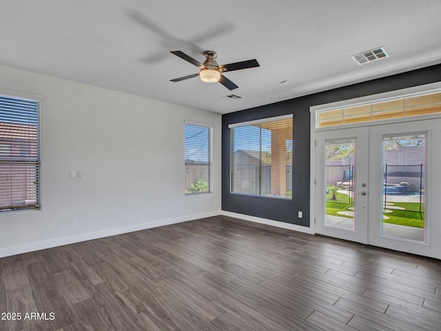 empty room with ceiling fan, dark wood-type flooring, visible vents, baseboards, and french doors