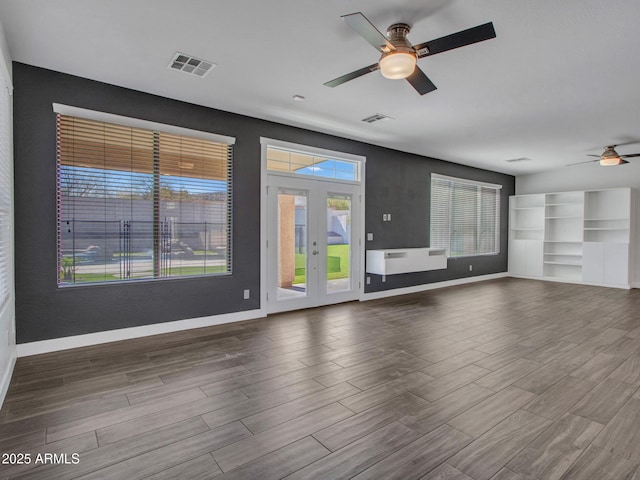 unfurnished living room with baseboards, visible vents, and wood finished floors