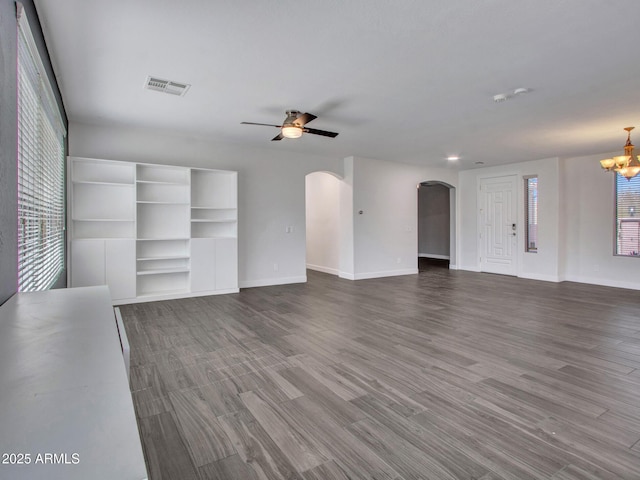 unfurnished living room with arched walkways, visible vents, wood finished floors, baseboards, and ceiling fan with notable chandelier