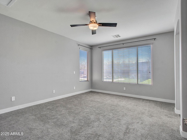 carpeted spare room with visible vents, ceiling fan, and baseboards