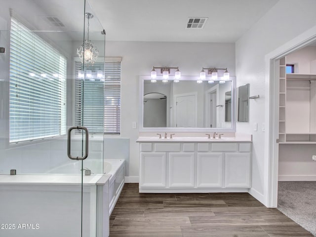 full bathroom featuring a garden tub, wood finished floors, a sink, and visible vents