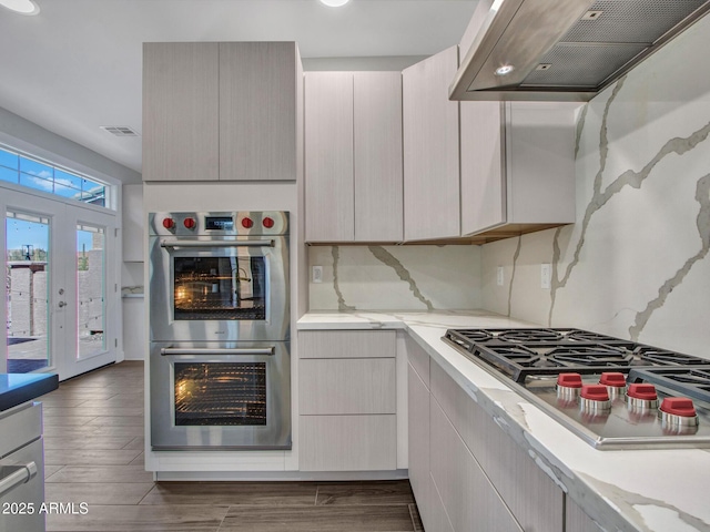 kitchen featuring under cabinet range hood, visible vents, stainless steel appliances, and wood finished floors