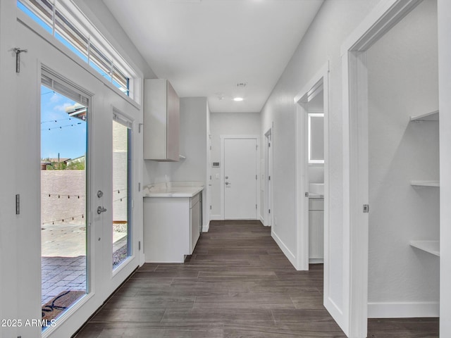 corridor featuring dark wood-style flooring and baseboards