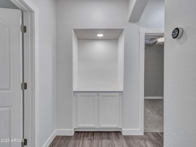 corridor with baseboards and wood finished floors