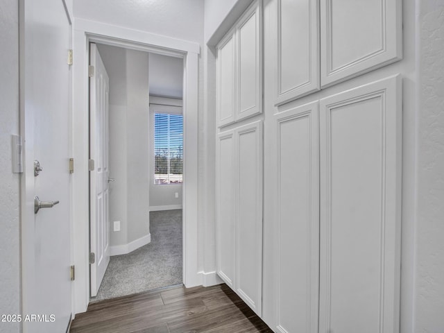 corridor with dark wood-style flooring and baseboards