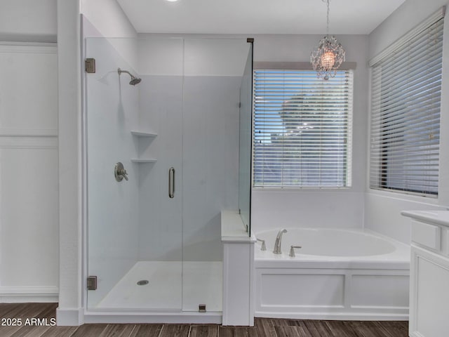 full bathroom featuring a stall shower, a garden tub, and wood finished floors