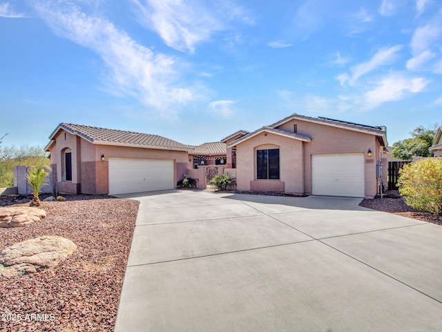 view of front facade featuring a garage, driveway, fence, and stucco siding