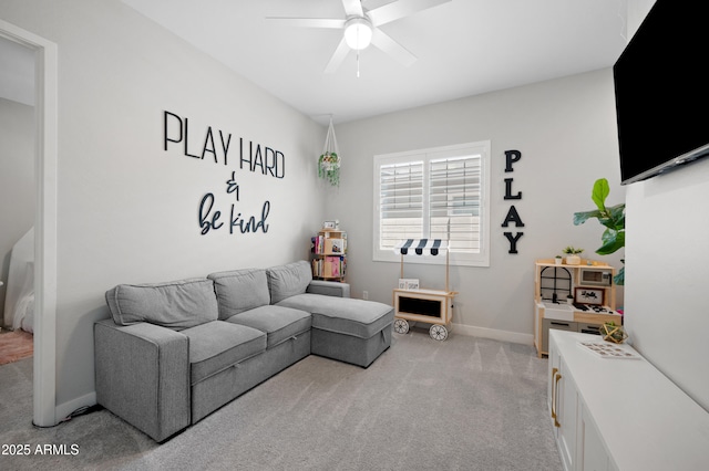 living area featuring light colored carpet, a ceiling fan, and baseboards