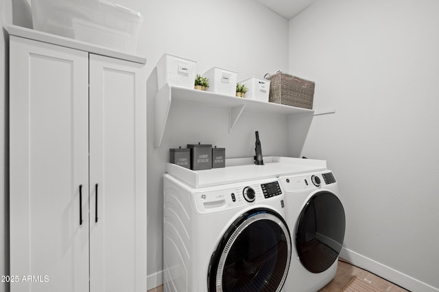 clothes washing area featuring laundry area, light wood-style flooring, baseboards, and washing machine and clothes dryer
