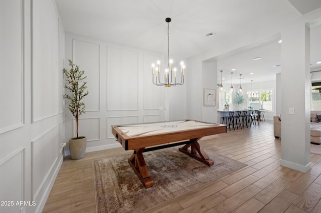 game room with light wood-style floors, a notable chandelier, visible vents, and a decorative wall