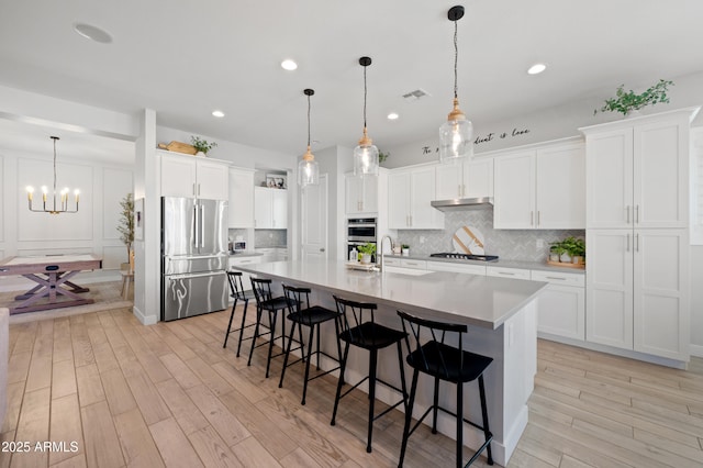 kitchen with visible vents, light wood finished floors, appliances with stainless steel finishes, and tasteful backsplash