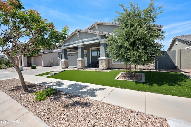 craftsman-style home featuring fence, stone siding, a front yard, a tiled roof, and an attached garage