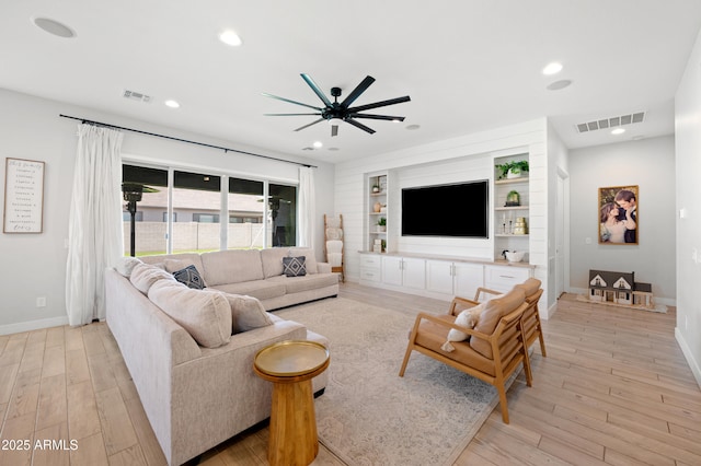 living room with visible vents, a ceiling fan, and light wood-type flooring