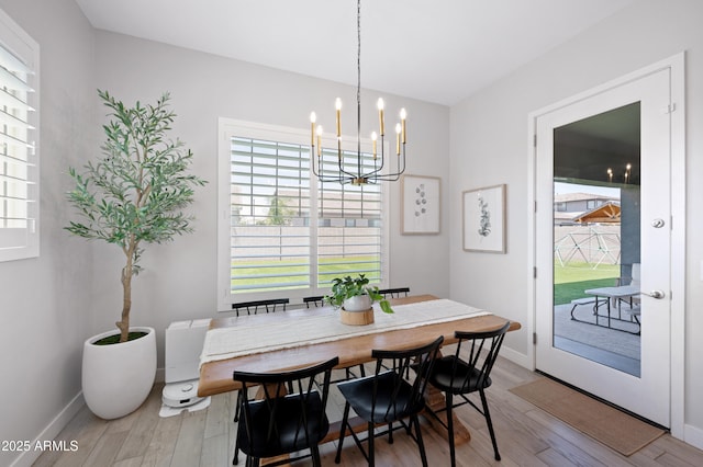 dining room featuring an inviting chandelier, plenty of natural light, and wood finished floors