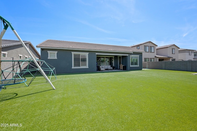 back of property featuring a yard, a fenced backyard, and stucco siding