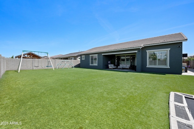 back of house featuring a tiled roof, a fenced backyard, a playground, a yard, and stucco siding