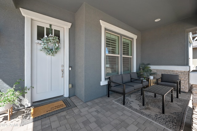 doorway to property featuring an outdoor hangout area, stucco siding, and stone siding