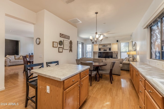 kitchen featuring a center island, an inviting chandelier, pendant lighting, a breakfast bar, and light wood-type flooring