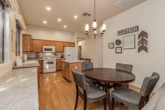 dining area with sink, a chandelier, and light wood-type flooring