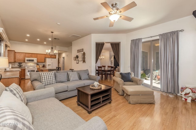 living room featuring ceiling fan with notable chandelier, light hardwood / wood-style floors, and sink