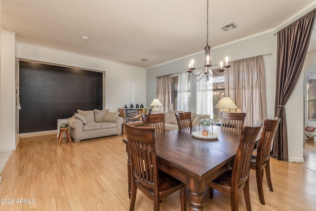 dining area featuring light hardwood / wood-style floors, ornamental molding, and an inviting chandelier