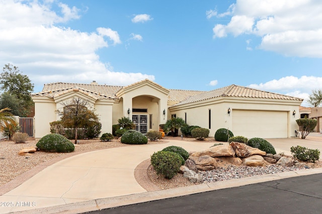 mediterranean / spanish home featuring a garage, driveway, a tile roof, and stucco siding