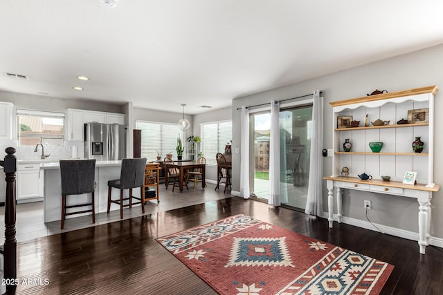 living area with visible vents, a healthy amount of sunlight, baseboards, and wood finished floors