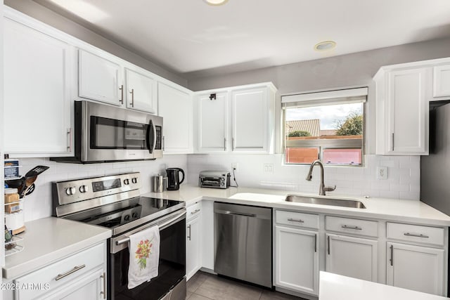 kitchen with a sink, stainless steel appliances, light countertops, and white cabinetry