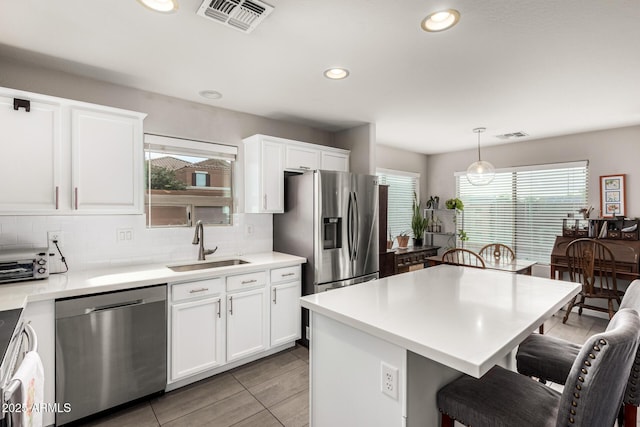 kitchen featuring visible vents, a breakfast bar, a sink, backsplash, and appliances with stainless steel finishes