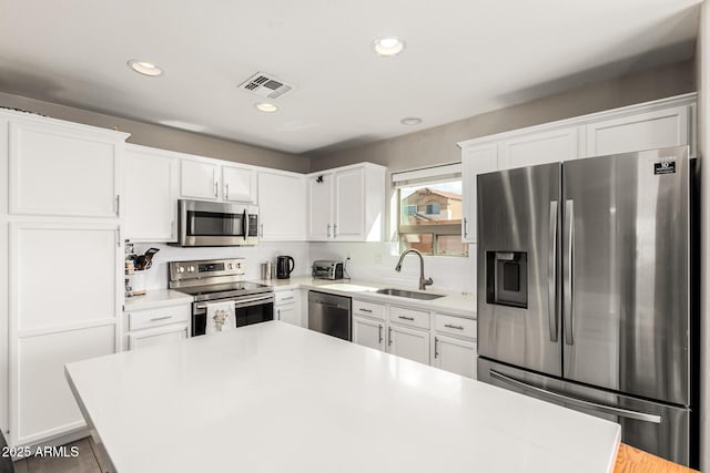 kitchen with visible vents, a sink, appliances with stainless steel finishes, white cabinets, and light countertops