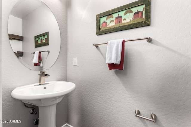 bathroom featuring a sink and a textured wall