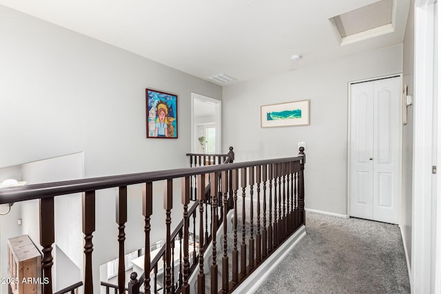 corridor with visible vents, baseboards, carpet, attic access, and an upstairs landing