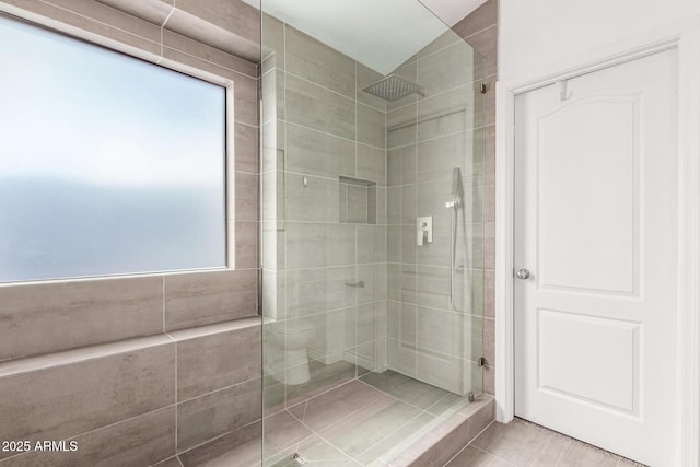 bathroom with a shower stall, toilet, and a wealth of natural light