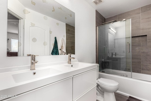 full bathroom with a sink, visible vents, toilet, and combined bath / shower with glass door