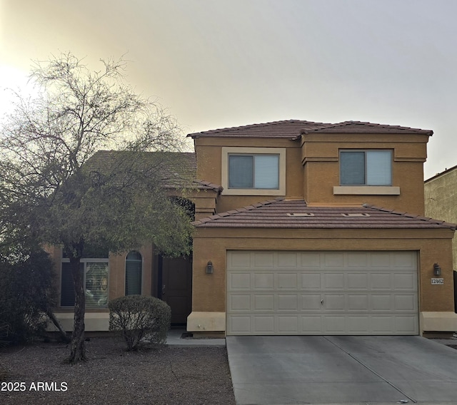 view of front facade featuring concrete driveway, a tiled roof, an attached garage, and stucco siding