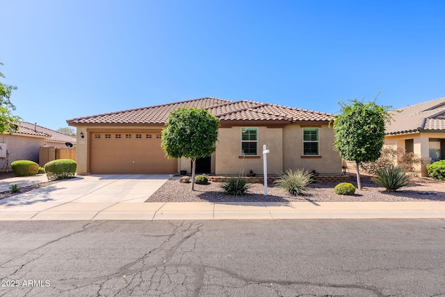 mediterranean / spanish home featuring driveway, stucco siding, a tiled roof, and a garage