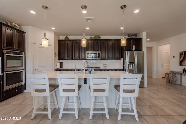 kitchen with light countertops, dark brown cabinetry, appliances with stainless steel finishes, and visible vents