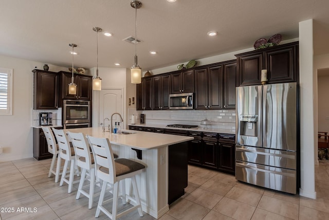 kitchen featuring light countertops, tasteful backsplash, a breakfast bar area, stainless steel appliances, and visible vents