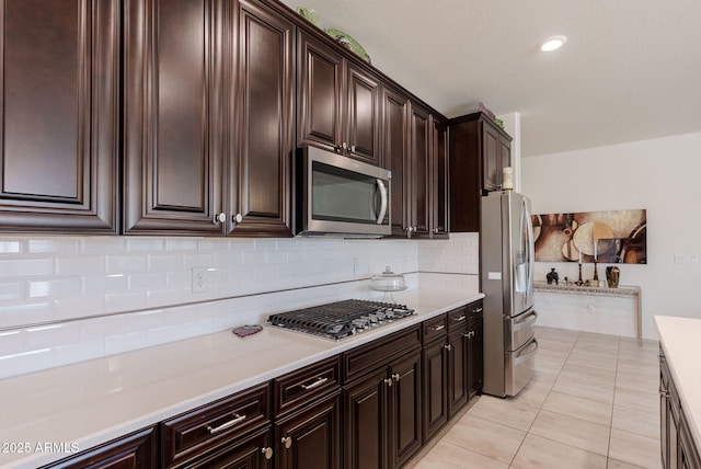 kitchen featuring dark brown cabinets, light countertops, decorative backsplash, and stainless steel appliances