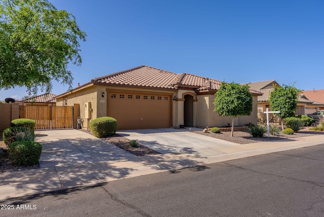 mediterranean / spanish-style home featuring concrete driveway, stucco siding, a tiled roof, a gate, and a garage