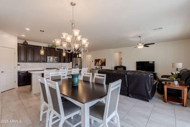 dining space featuring light tile patterned flooring, ceiling fan with notable chandelier, and visible vents